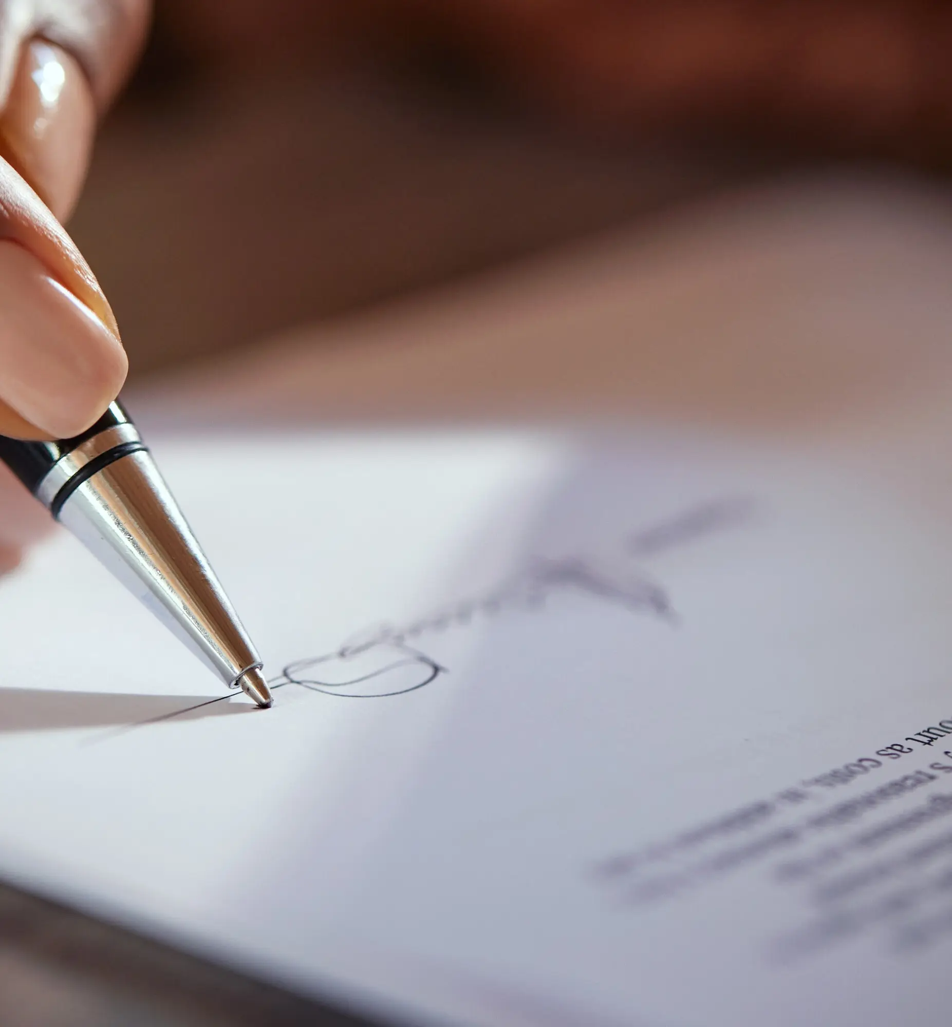 Close-up of a hand signing a document with a pen