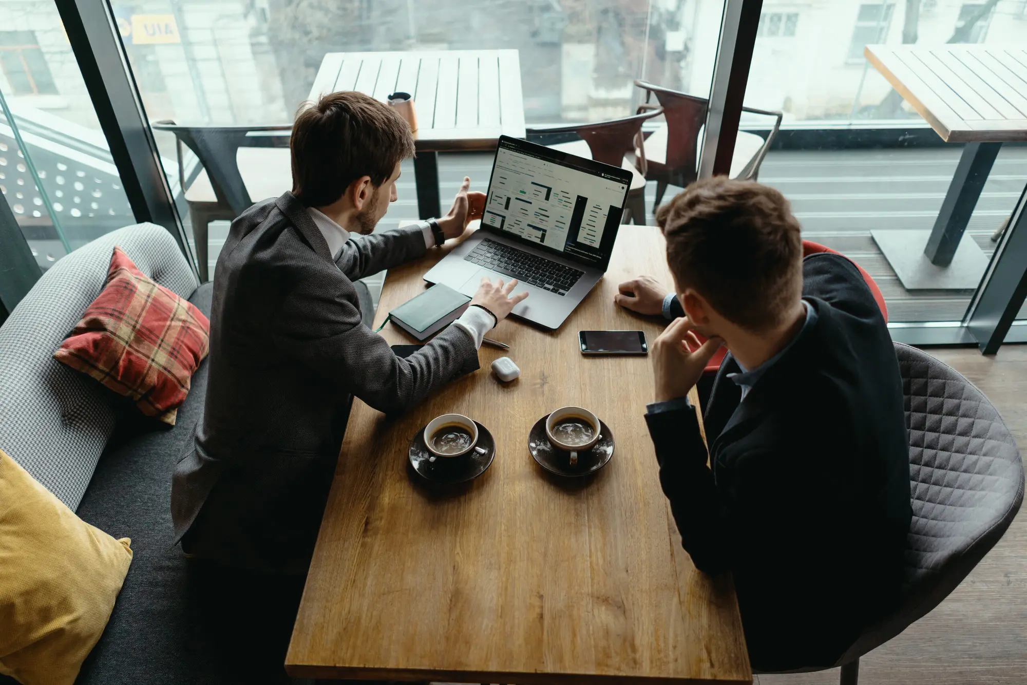 Two colleagues reviewing a bid on a laptop at a café table