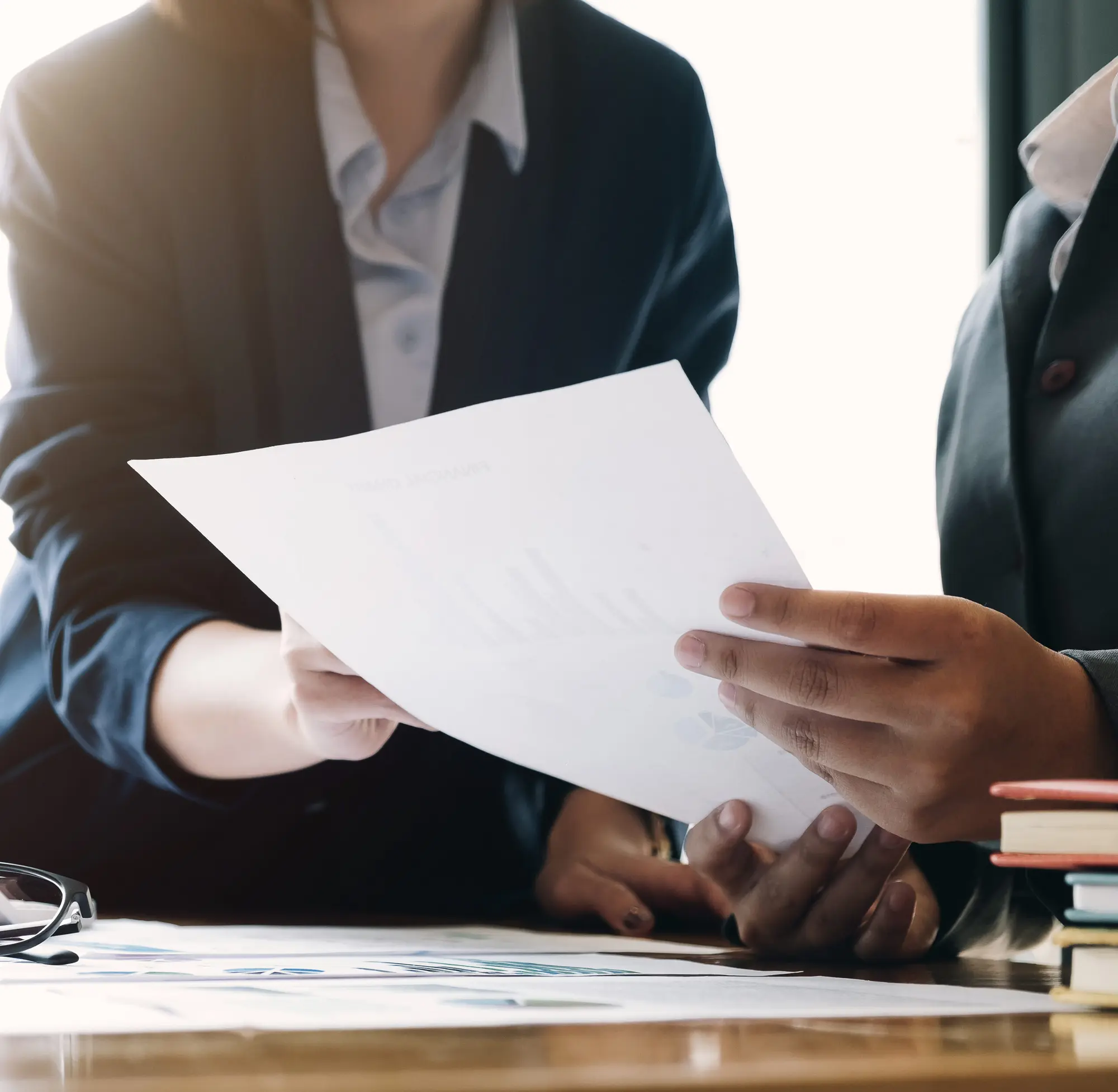 Two colleagues reviewing a printed financial report at a desk