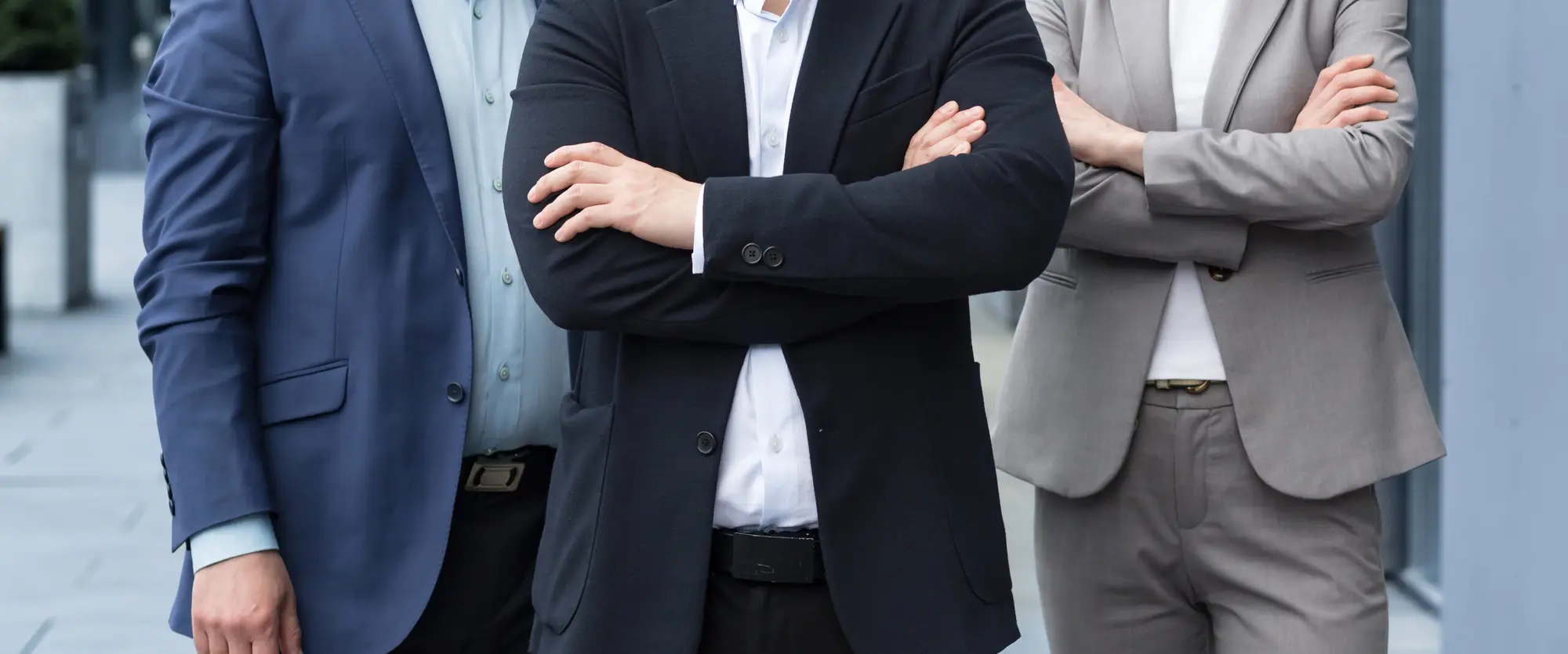 Three executives in business suits standing with arms crossed
